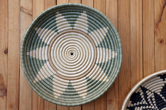 Traditional handwoven Agaseke basket bowl with sunburst pattern displayed on a wooden surface in Kigali, Rwanda
