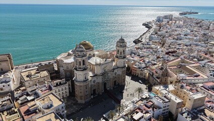 Aerial view of Cadiz Cathedral and its iconic golden dome by the sea. Cinematic drone shot of the historic landmark and the Atlantic Ocean coastline in Andalusia, Spain © Pablohasday