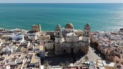 Aerial view of Cadiz Cathedral and its iconic golden dome by the sea. Cinematic drone shot of the historic landmark and the Atlantic Ocean coastline in Andalusia, Spain © Pablohasday