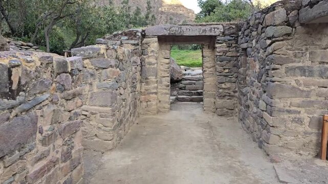 Ollantaytambo, Peru - 23 June 2024. First person POV moving through a ruined stone temple doorway at Ollantaytambo, featuring carved masonry walls, stone steps, and an ancient passage leading outdoors