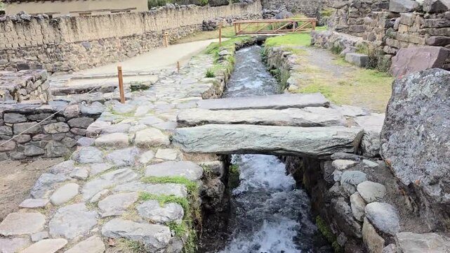 Ollantaytambo, Peru - 23 June 2024. Sacred stream running through the Temple of Ollantaytambo, surrounded by carved stone channels, ancient pathways, masonry walls, and Inca ruins.