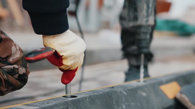 Worker securing rubber parking wheel stop with screwdriver close up