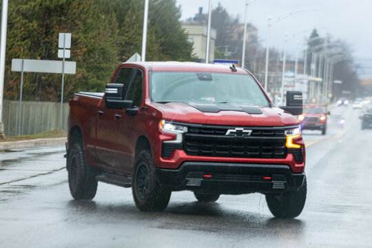 La Tuque, Canada, 07 May 2026 : Red Chevrolet Silverado pickup truck drives on a wet urban street during a rainy day