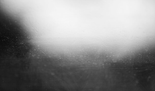 Dark gray grainy surface with bright white glow haze and soft water droplet