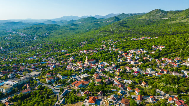 A charming Croatian Hreljin village nestled amidst lush green hills under a clear sky. Capturing the serene beauty of the Kvarner region's inland landscape.