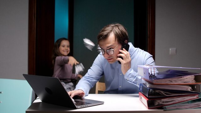 Overwhelmed father working from home on laptop and phone while a chaotic daughter throws objects, illustrating the challenges of managing parenthood and professional life