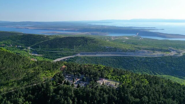 Aerial view of the modern highway A7 winding through lush green hills towards the serene Kvarner Gulf. A vibrant spring landscape perfect for a scenic drive along the Adriatic coast. Hreljin