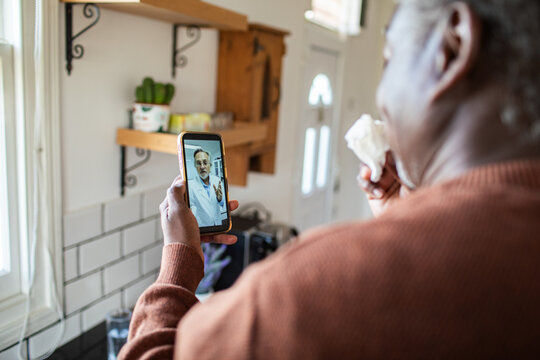 Sick man consulting doctor by video call in home kitchen