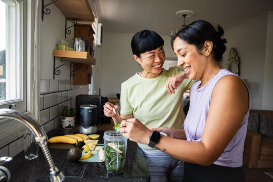 Smiling women making healthy smoothie in home kitchen