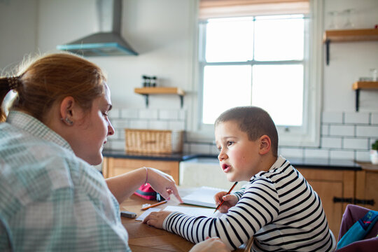 Parent helping child with homework at kitchen table