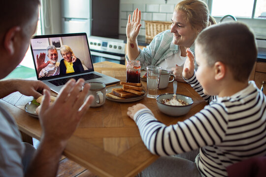 Family video calling grandparents during breakfast at home