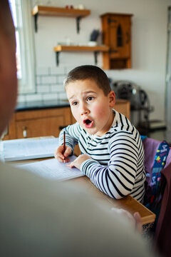 Elementary school boy doing homework at home kitchen table