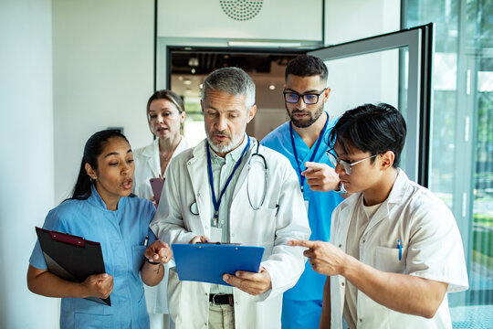 Doctors and nurses discussing patient chart in hospital hallway
