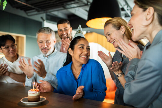 Coworkers celebrate birthday with cake in modern office