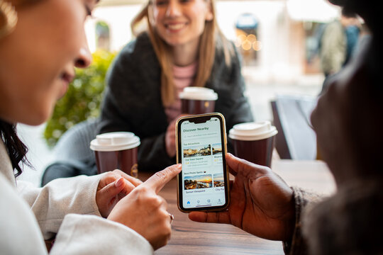 Friends planning travel on smartphone at outdoor cafe