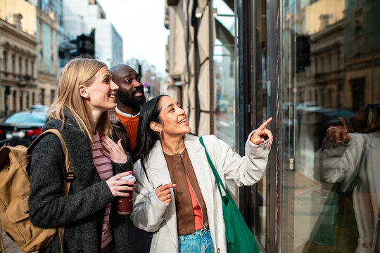 Three friends window shopping on city street