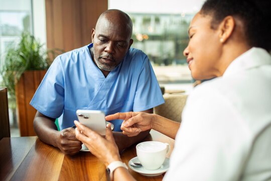 Healthcare colleagues reviewing mobile app at cafe