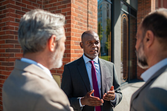 Senior executive leading discussion with colleagues outside office building