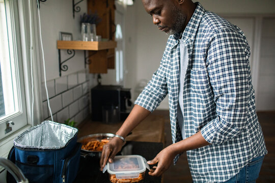 Adult man packing meal prep lunch in home kitchen