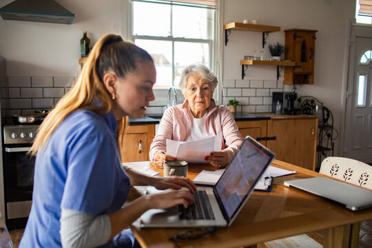 Home care nurse helping senior with paperwork at kitchen table