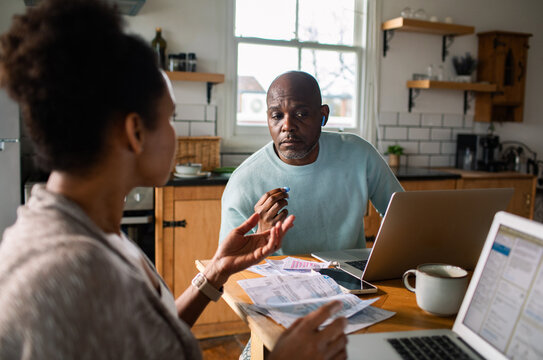 Couple discussing household finances with laptops in the kitchen