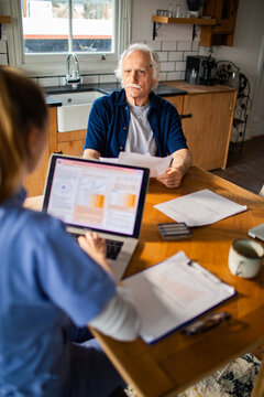 Senior man meeting with home healthcare nurse at kitchen table
