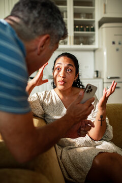 Couple arguing over smartphone in home kitchen