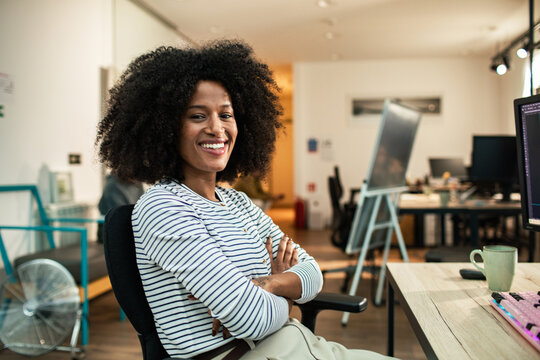 Smiling young professional woman at desk in modern creative office