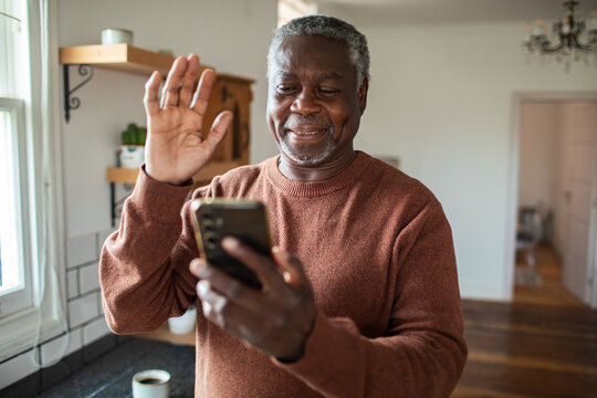 Smiling senior man video calling in home kitchen