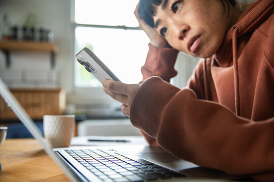 Worried woman reading phone notification at home office