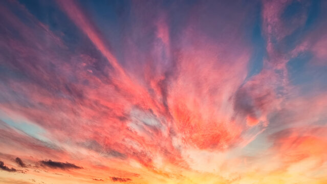 A vibrant sunset sky with hues of pink, orange, purple and blue clouds radiating out from the horizon