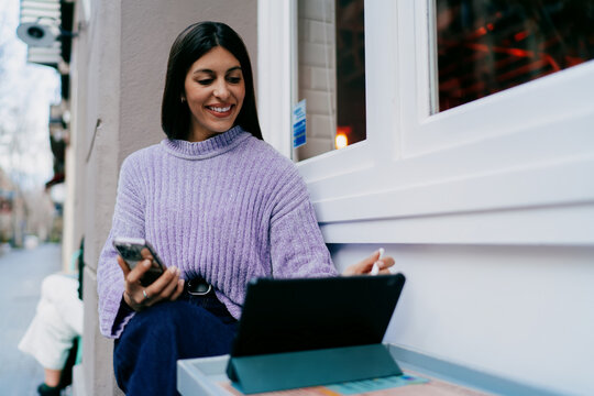 Successful woman using tablet device in modern office corridor with wooden walls. Digital nomad browsing online, creative designer working remotely, modern IT business concept, wireless connection.