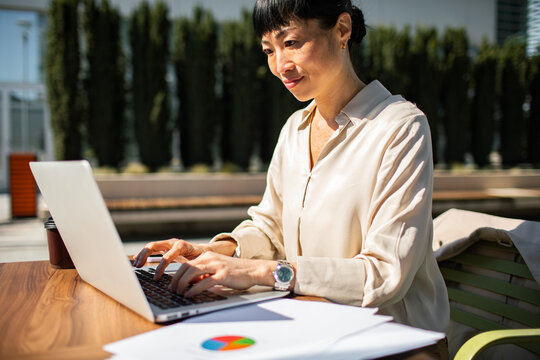 Professional woman working on laptop outdoors at office
