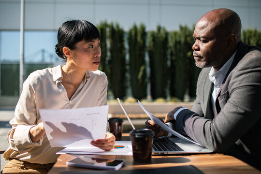 Two business professionals discussing reports outside an office