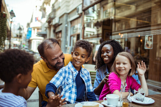 Parents and children laughing at outdoor city cafe