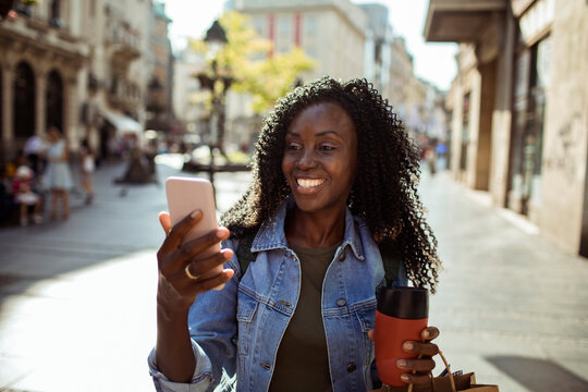 Smiling woman using smartphone on sunny city street