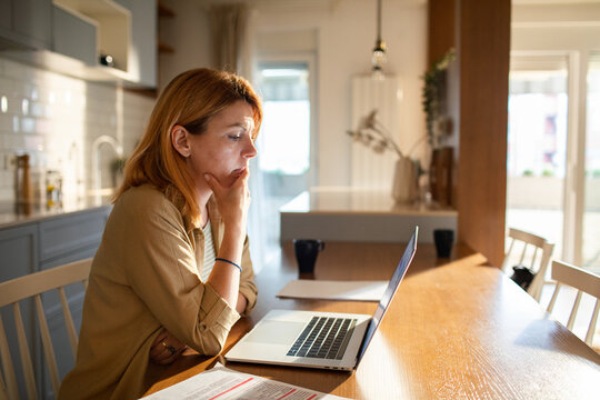 Woman paying bills online at home kitchen table