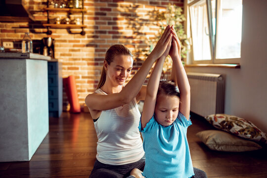 Mother helping child with yoga at home