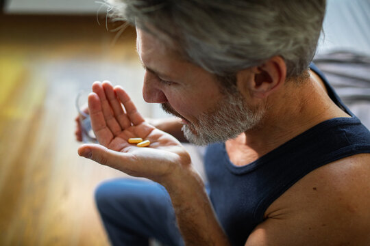 Middle-aged man taking vitamins at home