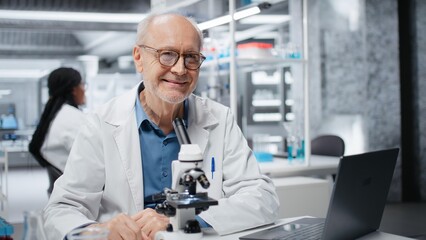Fototapeta premium Portrait of joyous researcher analyzing genetic samples with high tech microscopic equipment in laboratory. Cheerful senior man doing biotechnology advancement discovery in research clinic, camera B
