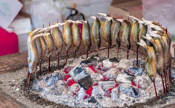 Grilled fish over fire at a food stall, Hanami Fest, Ueno Park, Tokyo, Japan