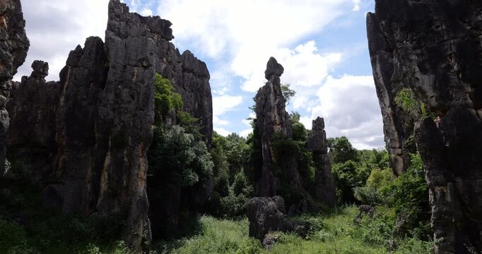 Stunning limestone karst formations resembling natural sculptures rise at Shilin Stone Forest in Yunnan. Camera turns to prominent pillar sharing characteristics with figure of mother and child