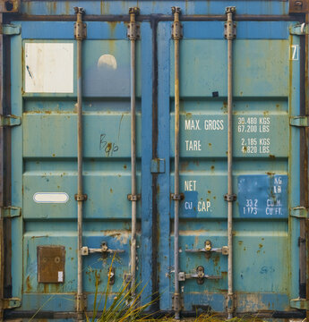 Detailed shot of weathered industrial container doors flanked by tall grass and moody lighting