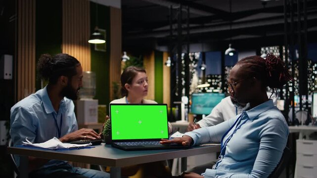 Green screen mockup laptop used by staff members in modern inclusive office. Coworkers presenting team leader key data statistics on chroma key isolated screen device after business audit.