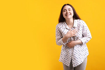 Obraz premium Happy woman laughing at joke on yellow background, space for text
