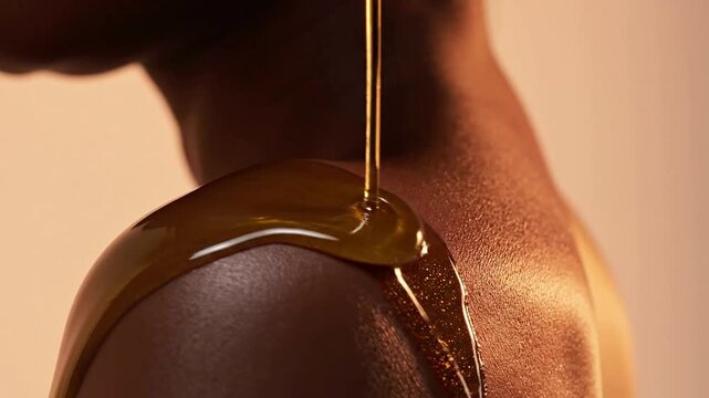 Close-Up Shot of Shimmering Body Oil Dripping on Smooth Skin from a Woman's Shoulder in Soft Warm Background Perfect for Luxury Beauty Product Advertisements