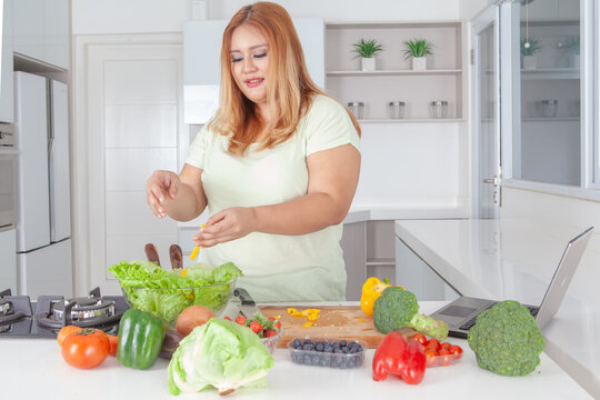 Curvy Asian Woman Preparing Fresh Healthy Salad in Modern Kitchen