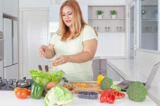 Plus Size Asian Woman Preparing Healthy Salad in Modern Kitchen