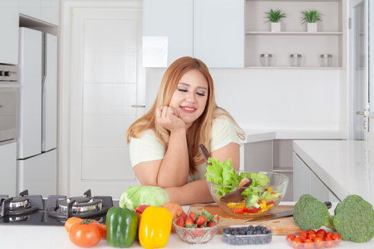 Satisfied Plus Size Asian Woman Enjoying Healthy Salad Preparation