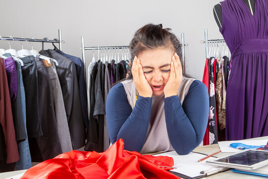 Stressed Female Fashion Designer with Headache in Clothing Atelier